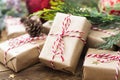 Close up Christmas gift boxes wraped in craft paper, fir branches, red baubles, pine cones over wooden table prepared for Royalty Free Stock Photo