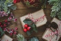 Close up Christmas gift boxes wraped in craft paper, fir branches, red baubles, pine cones over wooden table prepared for Royalty Free Stock Photo