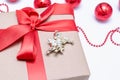 Close-up of a Christmas gift with a red ribbon and an angel next to the red Christmas balls on a white background. Festive Royalty Free Stock Photo