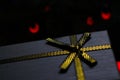 Close-up christmas gray present box with golden ribbon fir-tree branches on the dark background close-up. Side view. Red Royalty Free Stock Photo