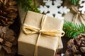 Close up of Christmas and New Year gift box wrapped in craft paper, wood ornaments, snow flake, fir tree branches, pine cones Royalty Free Stock Photo