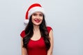 Close up Christmas Photo of Cheerful Woman with Beaming Smile in Red Dress and Santa Hat on Grey Background Royalty Free Stock Photo