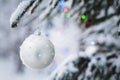 Close-up of a Christmas toy on a snow-covered lively tree in the winter forest on the background of lights Royalty Free Stock Photo