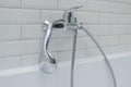 Close-up of chrome shower, faucet, in the bathroom covered decorative ceramic tiles with white glossy bricks. Royalty Free Stock Photo