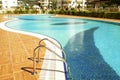 Swimming pool area of new luxury residential complex with tiles, chrome stairs handles and drains. Sunny beautiful day. Royalty Free Stock Photo