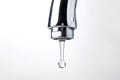 A close-up of a chrome tap with a single water droplet about to fall, set against a white background Royalty Free Stock Photo
