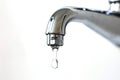 A close-up of a chrome tap with a single water droplet about to fall, set against a white background Royalty Free Stock Photo