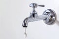 A close-up of a chrome tap with a single water droplet about to fall, set against a white background Royalty Free Stock Photo