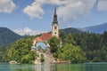 Close up of the church in the center of Bled Lake with several tourists walking by