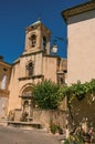 Close-up of church with steeple beside house with flowers in Lourmarin. Royalty Free Stock Photo