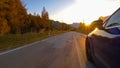 CLOSE UP: Cinematic shot of a blue car driving down a scenic road at sunrise.