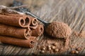 Close-up cinnamon sticks tied and ground cinnamon on a spoon of cardamom seeds on wooden background, macro Royalty Free Stock Photo