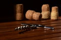 A close up of the classic corkscrew resting on the wooden brown table surface in front of wine corks. Isolated on black. Royalty Free Stock Photo