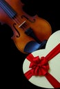 Close up of a classic violin and a heart shape gift box with a red ribbon bow Royalty Free Stock Photo