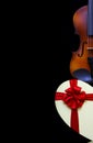 Close up of a classic violin and a heart shape gift box with a red ribbon bow Royalty Free Stock Photo