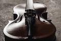 Close up of classical wooden cello on grey textured background in darkness.