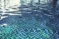 A close up of a clean swimming pool water at the light-blue tiled floor background. One swimming pool drain under rippling indoor