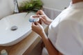 Close up of cleaning facial brush in hands of woman at sink in bathroom. Skincare tool. Royalty Free Stock Photo