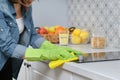 Woman hands in gloves washing and cleaning electric hob in kitchen Royalty Free Stock Photo