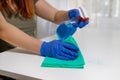 Woman cleaning table with blue color disinfectant spray and yellow towel. COVID-19 prevention sanitizing inside Royalty Free Stock Photo