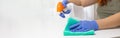 Woman cleaning table with green color disinfectant spray and yellow towel. COVID-19 prevention sanitizing inside Royalty Free Stock Photo