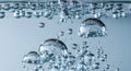 Close-up of clear water bubbles rising and forming on a light blue background Royalty Free Stock Photo