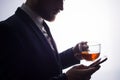 Close-up, on a clearance on a white background, the silhouette of a bearded handsome guy drinking tea from a transparent cup, uses