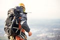 Close-up of a climber from the back in gear and with a backpack with equipment on the belt, stands on a rock, at high