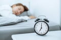 Close up Clock on the bed Asian woman wake up and disturbed by alarm clock early morning Royalty Free Stock Photo