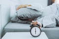 Close up Clock on the bed Asian woman wake up and disturbed by alarm clock early morning Royalty Free Stock Photo