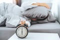 Close up Clock on the bed Asian woman wake up and disturbed by alarm clock early morning Royalty Free Stock Photo