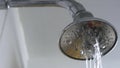 Close up of a clogged shower head in a bathroom wiith too little water coming through