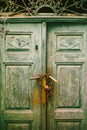 Close-up of closed doors of shabby green color with bandaged chains and locked door handles. Royalty Free Stock Photo