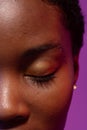 Close up of closed eye of african american woman with short hair on purple background Royalty Free Stock Photo