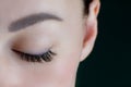 Close-up of closed eye with amazing long eyelashes, black eyeliner, perfect skin, eyebrow of unrecognizable young woman.