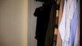 Close up of clothes in wardrobe near white wall. Concept. Side view of different shirts in full closet, details of Royalty Free Stock Photo