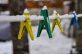 Close-up of clothespins for washing clothes, attached to a snow-covered rope against the blue sky and bright sun