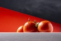 Close-up of a cluster of three wet red natural tomatoes on a white table with a red background and part of the sky. Photography Royalty Free Stock Photo