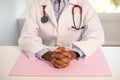 Close-up of clutched hands of female doctor sitting at table Royalty Free Stock Photo