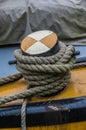 Close up of coarse rope tied around a coloured wooden bollard.