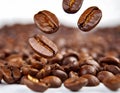 Close-up of coffee beans falling into a pile of coffee beans on a white background with varying shapes and sizes, and intense Royalty Free Stock Photo