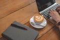 Close up of coffee cup with notebook and  woman hands using laptop. People and lifestyles concept. Freelance in coffee shop theme Royalty Free Stock Photo