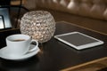 Close-up of coffee, digital tablet and lit candle on table