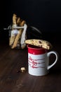 A close up of a coffee mug served with biscotti against a black background. Royalty Free Stock Photo