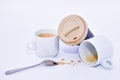 Close up of a coffee paper cup resting on two cups, with a metal spoon and some coffee splatter