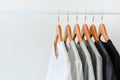 Collection of black, gray and white color hanging on wooden clothes hanger in closet or clothing rack