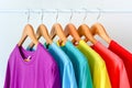 Collection of colorful rainbow t-shirts hanging on wooden clothes hanger on clothing rack over white background Royalty Free Stock Photo