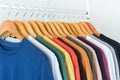 Close up collection of colorful t-shirts hanging on wooden clothes hanger in closet or clothing rack over white background Royalty Free Stock Photo