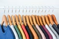 Close up collection of colorful t-shirts hanging on wooden clothes hanger in closet or clothing rack over white background Royalty Free Stock Photo