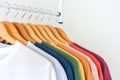 Close up collection of colorful t-shirts hanging on wooden clothes hanger in closet or clothing rack over white background, copy Royalty Free Stock Photo